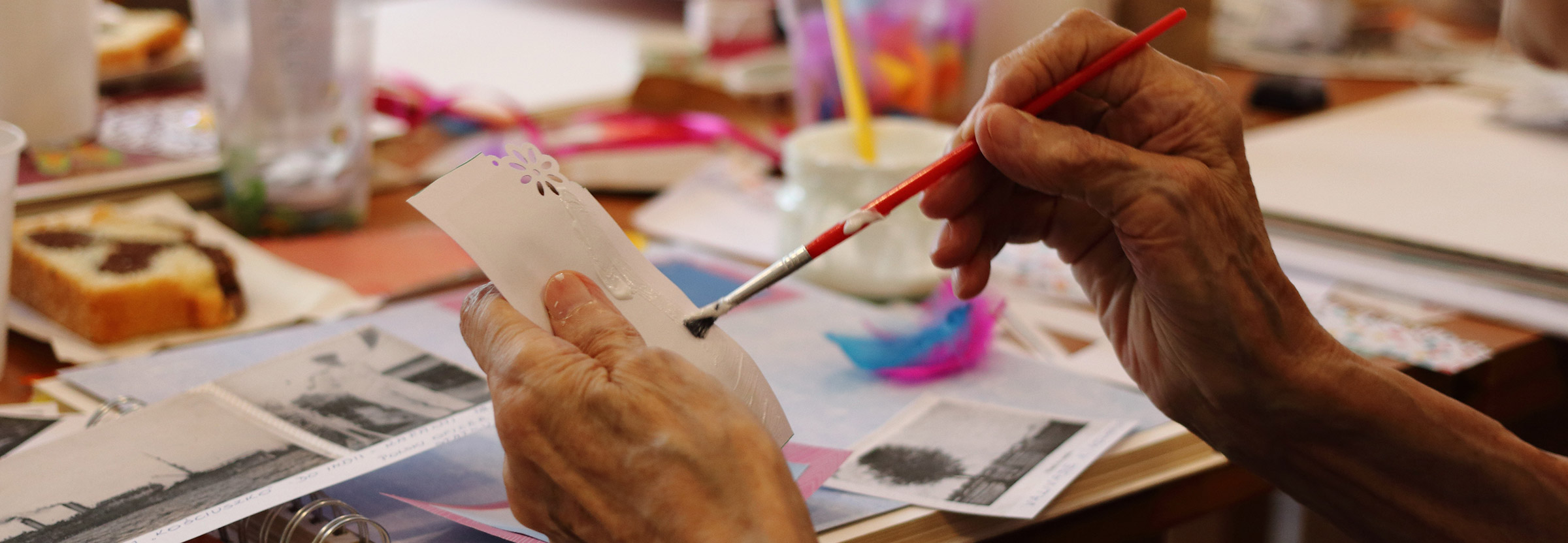 Closeup of an elderly woman's hands as she paints a card